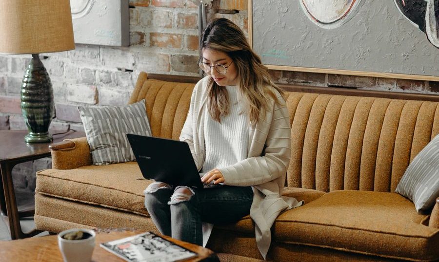 ソファでノートPCを開く女性