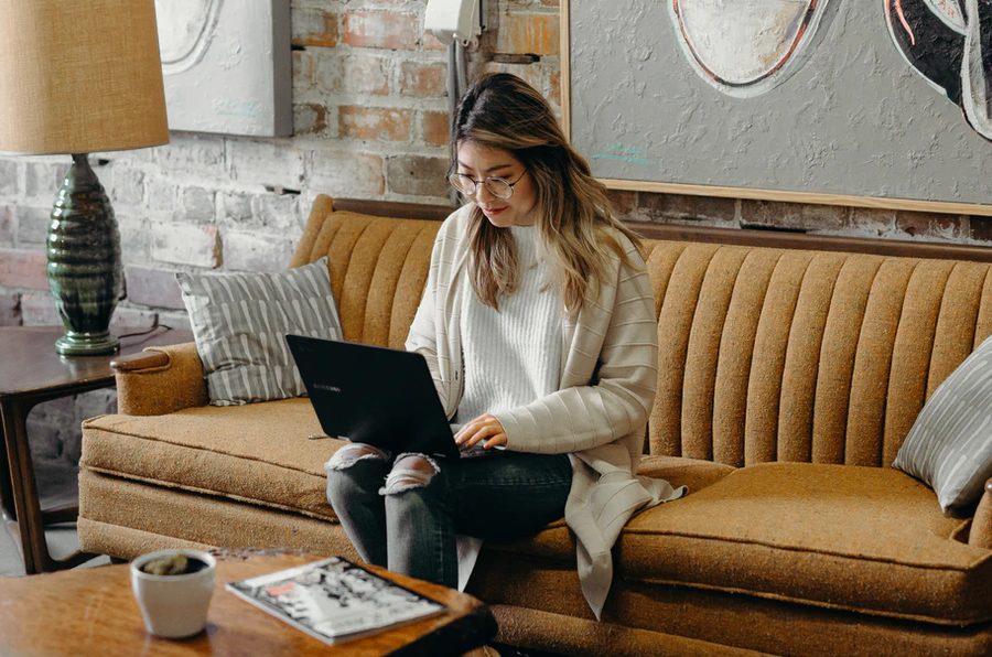 ソファでノートPCを開く女性